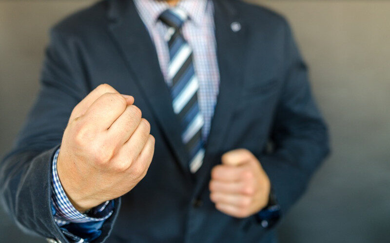 un uomo visto a mezzo busto che mostra i pugni in segno di sfida