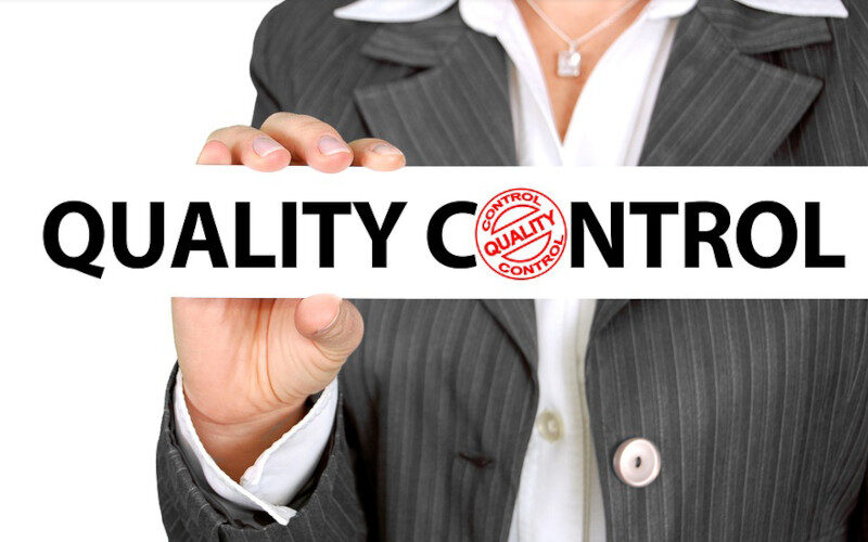 donna che tiene in mano un cartello con scritto "quality control"
