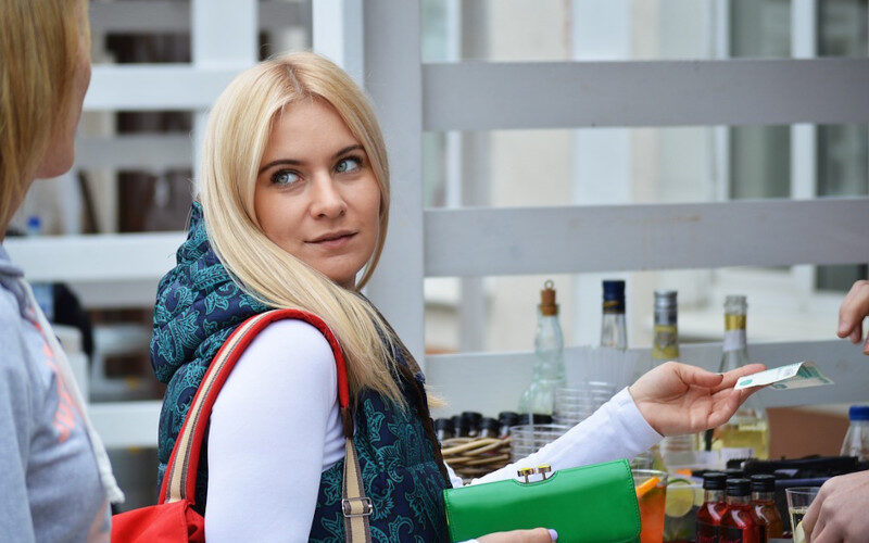 ragazza che sta facendo un acquisto presso un negozio e si gira verso una persona alle sue spalle